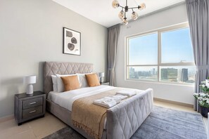 A modern bedroom with a large bed, a nightstand, a framed artwork, and a view of the city through a large window. - Silkhaus Cozy 1BR With Balcony Pool Gym on Reem Island (Abu Dhabi)