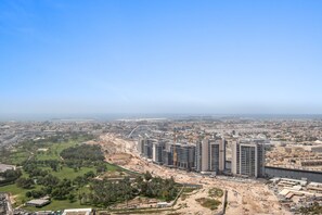 A high-rise building with multiple floors, surrounded by a construction site and a park. - Silkhaus New High Floor Studio Aykon City (Dubai)
