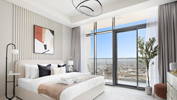 A modern hotel room with a large bed, a city view, and a balcony. - Silkhaus New High Floor Studio Aykon City (Dubai)