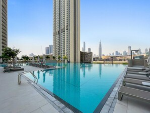 Ein Pool auf dem Dach mit Liegestühlen und einer Stadtkulisse im Hintergrund.