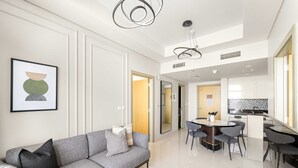 A modern living room with a grey sofa, a coffee table, and a dining area with a round table and chairs. - Silkhaus Elite 2bdr Near Safa Park Aykon City (Dubai)