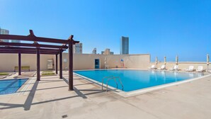 Une piscine sur le toit, agrémentée d’une pergola, de chaises longues et offrant une vue panoramique sur la ville.