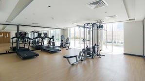 Une salle de sport spacieuse équipée de tapis de course, de vélos elliptiques et d'appareils de musculation.