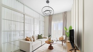 A modern living room with a sofa, coffee table, and TV. - Silkhaus Cozy 2 BR Full Amenities (Dubai)