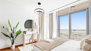Une chambre moderne avec un grand lit, une table de chevet, un miroir, une plante en pot et une vue sur le paysage grâce à de grandes fenêtres.