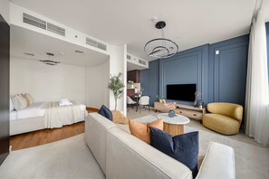 A modern living room with a sofa, a coffee table, and a TV. There is a dining area with a table and chairs. - Silkhaus Cozy Studio Sky Gardens Heart of Difc (Dubai)