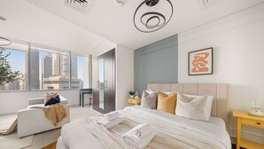 A modern bedroom with a large bed, a sofa, and a view of tall buildings. - Silkhaus Cozy Studio Sky Gardens Heart of Difc (Dubai)