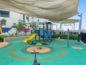 A playground with a slide, swings, and a climbing structure. - Silkhaus Studio Escape Business Bay (Dubai)