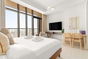 A hotel room with a large bed, a TV, a desk with chairs, and a city view. - Silkhaus Studio Escape Business Bay (Dubai)