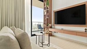 Ett modernt vardagsrum med en stor platt-TV, en soffa och ett litet bord med dekorativa föremål.