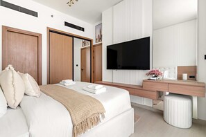 A modern bedroom with a large bed, a TV, a wooden wardrobe, and a bedside table with a lamp and flowers. - Silkhaus Modern 1BR Stay Binghatti Onyx New (Dubai)