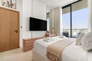 A modern hotel room with a large bed, a flat-screen TV, a wooden wardrobe, a bedside table with a lamp, and a city view. - Silkhaus Modern 1BR Stay Binghatti Onyx New (Dubai)