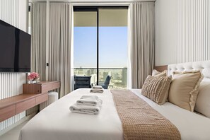 A hotel room with a large bed, a TV, a desk, and a view of the city. - Silkhaus Modern 1BR Stay Binghatti Onyx New (Dubai)