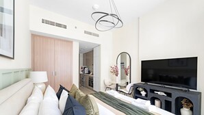 A modern hotel room with a bed, a TV, a desk, and a kitchenette. - Silkhaus Chic Studio Skyline View MBR City (Dubai)
