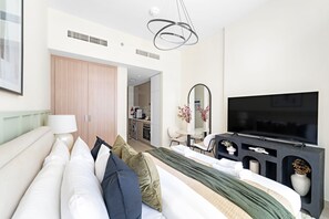 Ein modernes Hotelzimmer mit Bett, Fernseher, Schreibtisch und einer Küchenzeile.