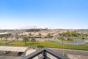 A view of a modern urban area with a roundabout, palm trees, and a construction site with a crane. - Silkhaus Chic Studio Stay Near Ferrari World (Abu Dhabi)