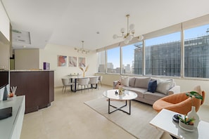 A modern living room with a sofa, coffee table, and a dining area with chairs and a table. - Silkhaus Expansive 2bdr Heart of Difc (Dubai)