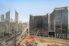 A modern building under construction with a large glass facade, surrounded by a busy urban street with other high-rise buildings. - Silkhaus Expansive 2bdr Heart of Difc (Dubai)