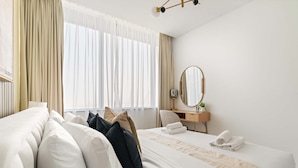 A hotel room with a large bed, a desk, a chair, a mirror, and a window with curtains. - Silkhaus Comfy 1bdr Sky Gardens in Difc NEW (Dubai)
