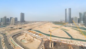 A cityscape with modern high-rise buildings, a large construction site, and a river. - Silkhaus New 2bdr in Julphar Near Adgm (Abu Dhabi)