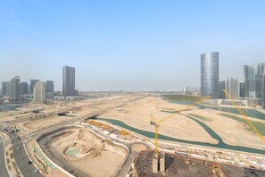 A cityscape with modern high-rise buildings, a large construction site, and a river. - Silkhaus New 2bdr in Julphar Near Adgm (Abu Dhabi)