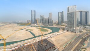 A modern cityscape with high-rise buildings, a river, and construction cranes. - Silkhaus New 2bdr in Julphar Near Adgm (Abu Dhabi)