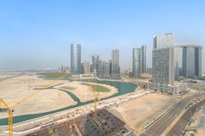 A modern cityscape with high-rise buildings, a river, and construction cranes. - Silkhaus New 2bdr in Julphar Near Adgm (Abu Dhabi)