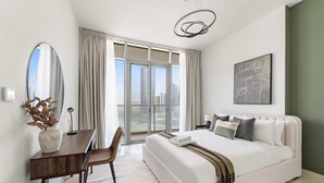 A modern bedroom with a large bed, a desk, and a view of the city through large windows. - Silkhaus New 2bdr in Julphar Near Adgm (Abu Dhabi)