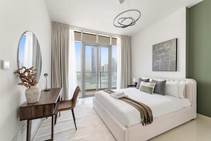 A modern bedroom with a large bed, a desk, and a view of the city through large windows. - Silkhaus New 2bdr in Julphar Near Adgm (Abu Dhabi)