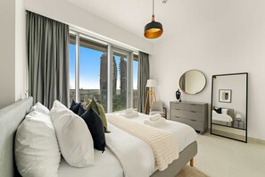 A modern bedroom with a large bed, a bedside table, a mirror, and a view of a cityscape through large windows. - Silkhaus Elite 3BR Near Dubai Watercanal in Al Wasl (Dubai)
