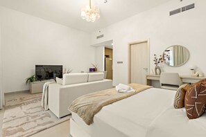 A modern bedroom with a bed, a sofa, a TV, a desk, and a mirror. - Silkhaus Signature Studio Yas Golf Collection (Abu Dhabi)
