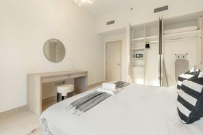 A modern hotel room with a bed, a desk, a mirror, and a walk-in closet. - Silkhaus Premier 1BR Yas Golf Collection (Abu Dhabi)