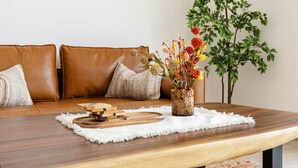 A wooden dining table with a white placemat, a vase with dried flowers, and a wooden board game. - Silkhaus Serene 1bdr Retreat in Yas Island (Abu Dhabi)