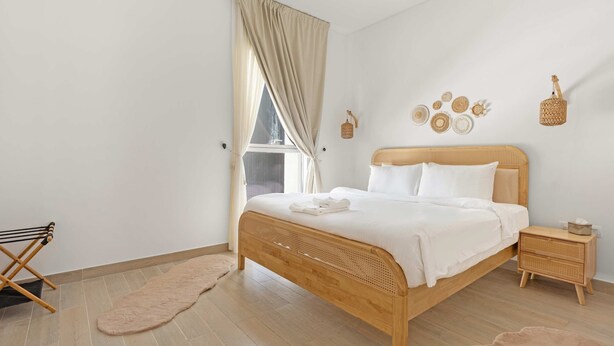 A bedroom with a wooden bed, a bedside table, a nightstand, a window with curtains, and wall decor. - Silkhaus Serene 1bdr Retreat in Yas Island (Abu Dhabi)