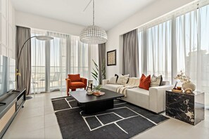 A modern living room with a black coffee table, white sofa, and orange armchair. - Silkhaus Elite 1bdr Canal Front Tower Al Wasl (Dubai)