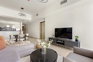A modern living room with a sofa, a coffee table, a TV, and a dining area with chairs and a table. - Silkhaus Serene 1bdr Getaway in Reem Island (Abu Dhabi)