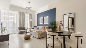 Een moderne woonkamer met een bank, eettafel, stoelen en een groot raam met gordijnen.