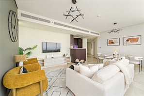 A modern living room with a sofa, a TV, and a dining area. - Silkhaus 2bdr Heart of Difc in Sky Gardens (Dubai)