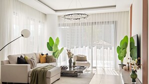 Een moderne woonkamer met een bank, salontafel en grote planten.