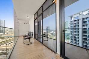Een balkon met uitzicht op een stadsgezicht, een glazen deur en twee stoelen.