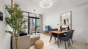 Una sala de estar moderna con comedor, ventanas grandes y vistas a la ciudad.