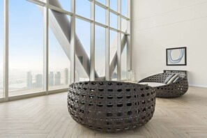 A modern room with large windows, a unique geometric wall, and two bean bags. - Silkhaus 64floor PH Ballroom Hall Private Pool (Abu Dhabi)