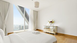 Ein modernes Hotelzimmer mit einem großen Bett, einem Schminktisch und Blick auf die Stadt.
