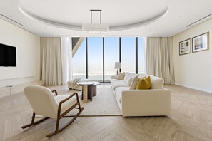 A modern living room with a sofa, a rocking chair, a coffee table, and a TV. - Silkhaus 64floor PH Ballroom Hall Private Pool (Abu Dhabi)