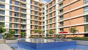 A modern building with a central pool area, surrounded by balconies and outdoor seating. - Silkhaus Luxurious 3BR Maid Dubai Hills (Dubai)