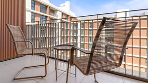 A balcony with two chairs and a small table, overlooking a modern building with large windows. - Silkhaus Luxurious 3BR Maid Dubai Hills (Dubai)