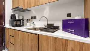 Een moderne keuken met houten kastjes, een roestvrijstalen spoelbak, een koffiezetapparaat en een doos met een logo.