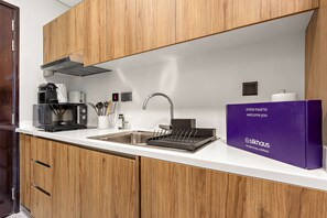 Eine moderne Küche mit Holzausstattung, einer Edelstahlspüle, einer Kaffeemaschine und einer Markenverpackung.