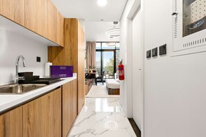 A modern kitchen with wooden cabinets, a stainless steel sink, and a marble floor. - Silkhaus New Building Studio Near Galleria Mall (Abu Dhabi)
