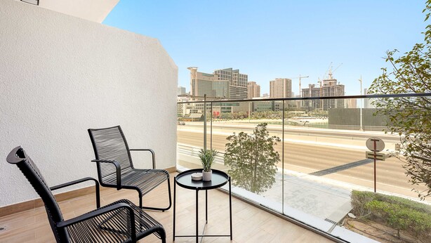 Een balkon met twee stoelen, een tafeltje en een bloempot.